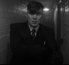 a man in a suit and tie standing next to a brick wall