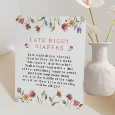 a white vase with flowers next to a card that says late night diapers