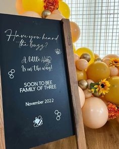 a chalkboard sign in front of balloons and flowers