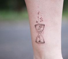 a small tattoo on the leg of a woman's foot with an hourglass