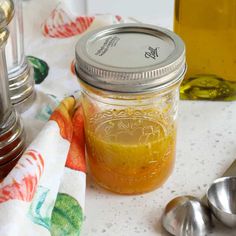 a jar filled with liquid sitting on top of a table next to measuring spoons