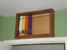 a wooden box filled with colorful towels on top of a white door frame in a green room