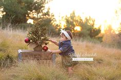 a baby girl is playing with an apple tree in the grass at sunset, wearing a dress and headband