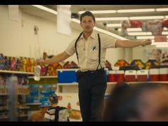 a man standing on top of a table in a store next to shelves filled with toys