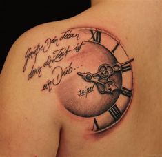 a clock tattoo on the back of a woman's shoulder, with words written in cursive writing