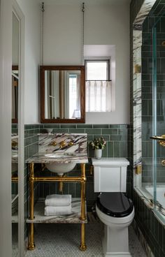 a white toilet sitting next to a sink in a bathroom under a mirror above it