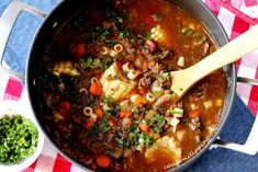 a pot filled with soup and vegetables on top of a checkered table cloth