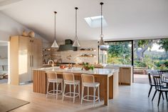 an open kitchen and dining room area with skylights above the countertop, along with bar stools