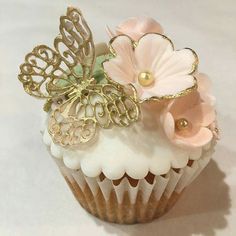 there is a cupcake decorated with flowers and butterfly decorations on it's side