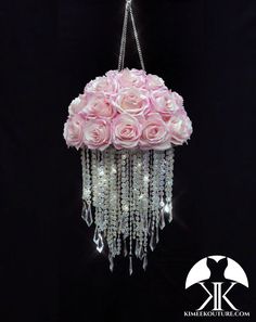 a chandelier with pink roses hanging from it's sides and crystal beads