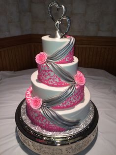 a three tiered cake with pink and silver decorations