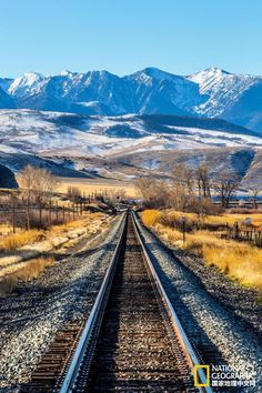 an old train track in the middle of nowhere, with mountains in the back ground