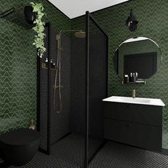 a black and white bathroom with green tiles on the walls, toilet, sink and shower stall