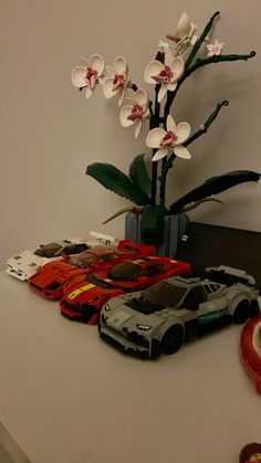 a vase filled with white flowers sitting on top of a table next to toy cars