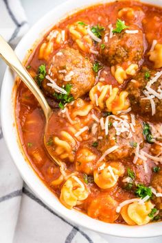 a white bowl filled with meatballs and pasta soup on top of a checkered table cloth