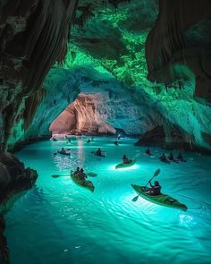 several kayakers are in the blue cave with green lights on their faces and water around them