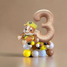 an animal figurine sitting on top of balloons in the shape of number three