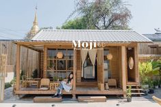 a woman sitting on the porch of a small wooden house with an awning over it