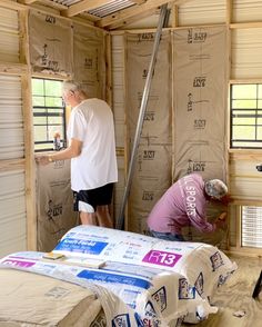 two men are working on the insulation in a small room that's being built