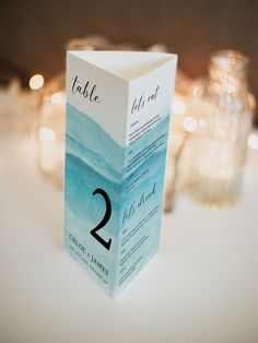 the table numbers are placed on top of each other in front of candles and watercolor paper