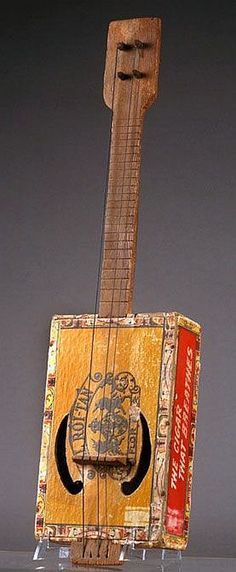 a small wooden instrument with an intricate design on the body and neck, sitting on top of a glass shelf