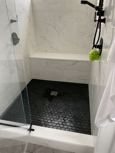 a bathroom with a black and white tile floor, shower head, and glass door