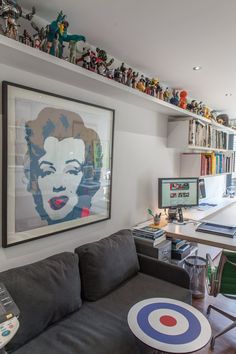 a living room filled with furniture and a painting on the wall above a computer desk