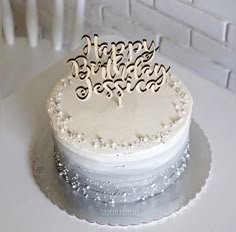 a birthday cake with white frosting and decorative decorations on the top is sitting on a table