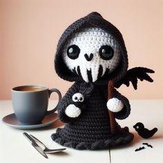 there is a crocheted doll with a coffee cup and spoon on the table