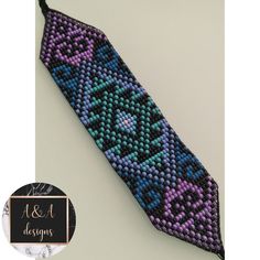 a purple and blue beaded tie sitting on top of a white table next to a badge