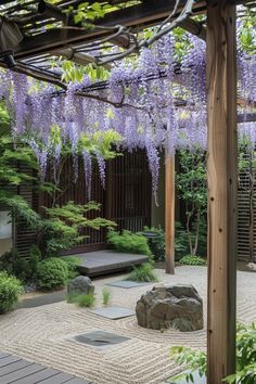 a japanese garden with purple flowers hanging from the pergolated trellis and rocks