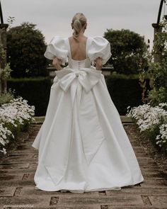 a woman in a wedding dress walking down a path