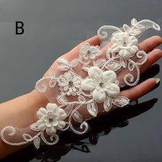 a woman's hand wearing a white lace wrist corsage with flowers on it