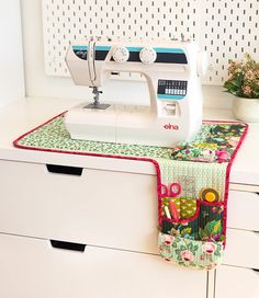 a sewing machine sitting on top of a white dresser next to a potted plant