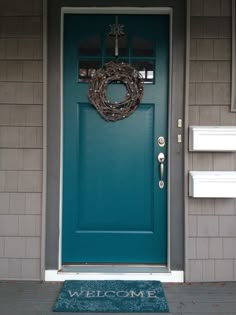 a blue front door with a welcome mat