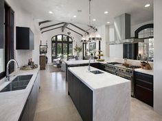 a large kitchen with white counter tops and black appliances in the middle of the room