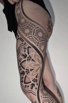 a woman's leg with tattoos on it and an intricate design in black ink