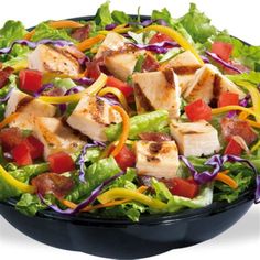 a salad with chicken, lettuce and tomatoes in a black bowl on a white background