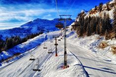 a ski lift going up the side of a snow covered mountain with trees in the background