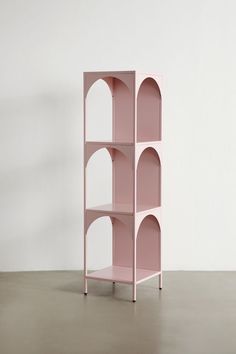 a pink shelf sitting on top of a floor next to a white wall with arched doorways