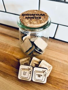 three coasters sitting on top of a wooden table next to a jar filled with magnets