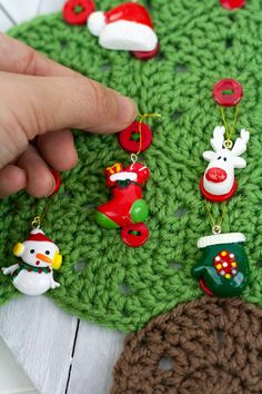 a hand is pointing at ornaments on a crocheted christmas tree ornament