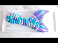 there is a cake shaped like a fish on the plate with blue and purple icing