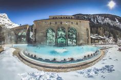 people are sitting in the snow near a large hot tub with steam coming out of it