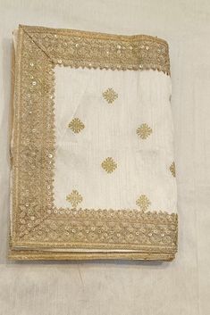 a white cloth with gold sequins on it and a square shaped object in the middle