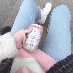 a person sitting on the ground holding a can of rose lemonade in their hand