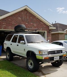 a white suv parked in front of a house with a car attached to the roof