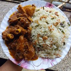 a paper plate topped with rice and meat