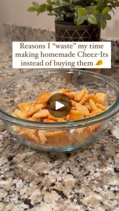 a glass bowl filled with cheetos sitting on top of a counter next to a potted plant