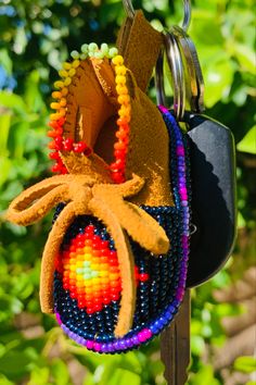 a keychain hanging from a tree with beads on it